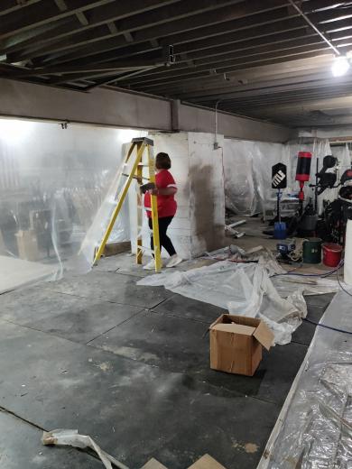 person moving a ladder while painting a basement wall