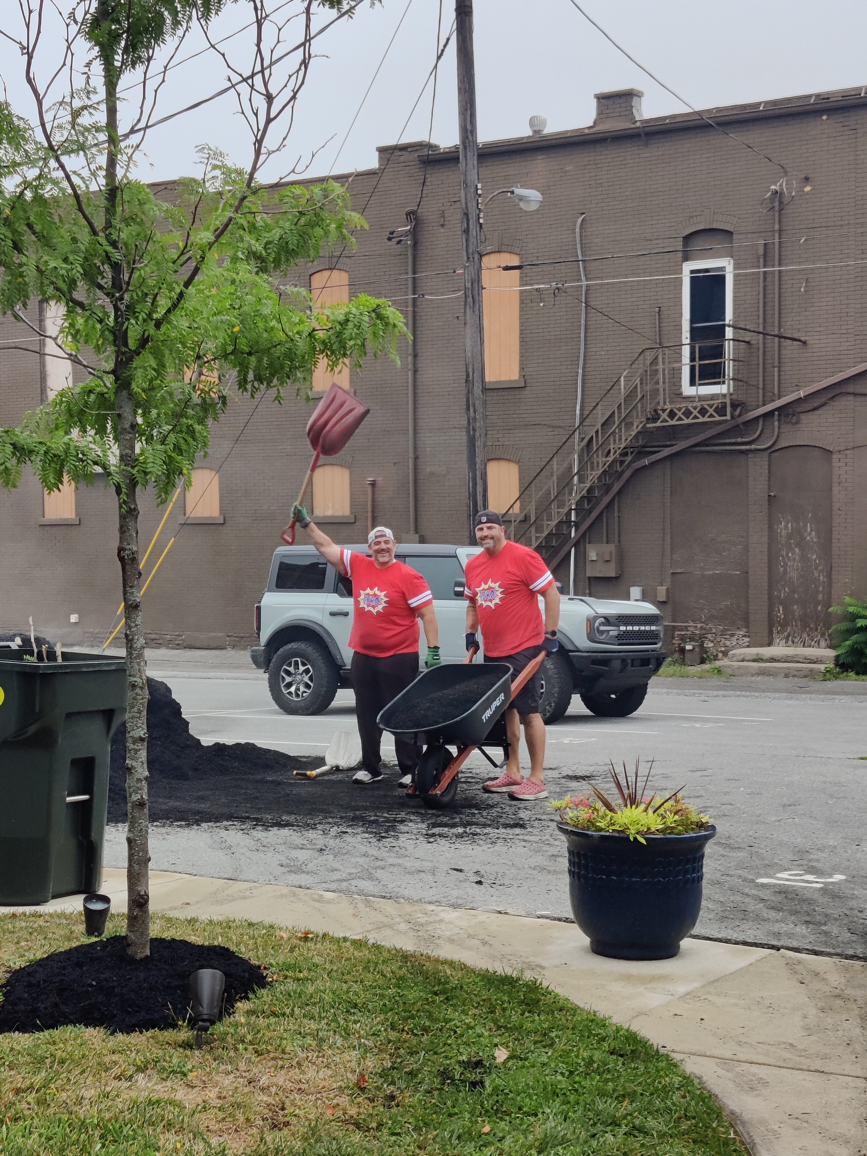 men with wheelbarrow of mulch 