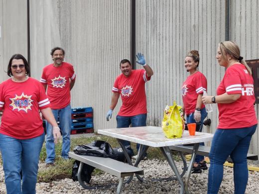 group of people in red shirts standing around a picnic table