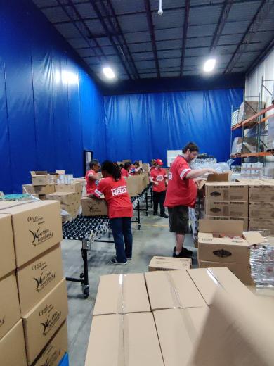 group of people packing food boxes on conveyor belt