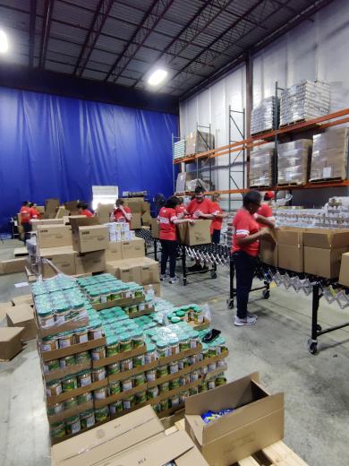 group of people packing food boxes on conveyor belt