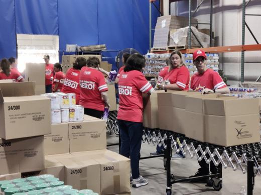 group of people packing food boxes on conveyor belt