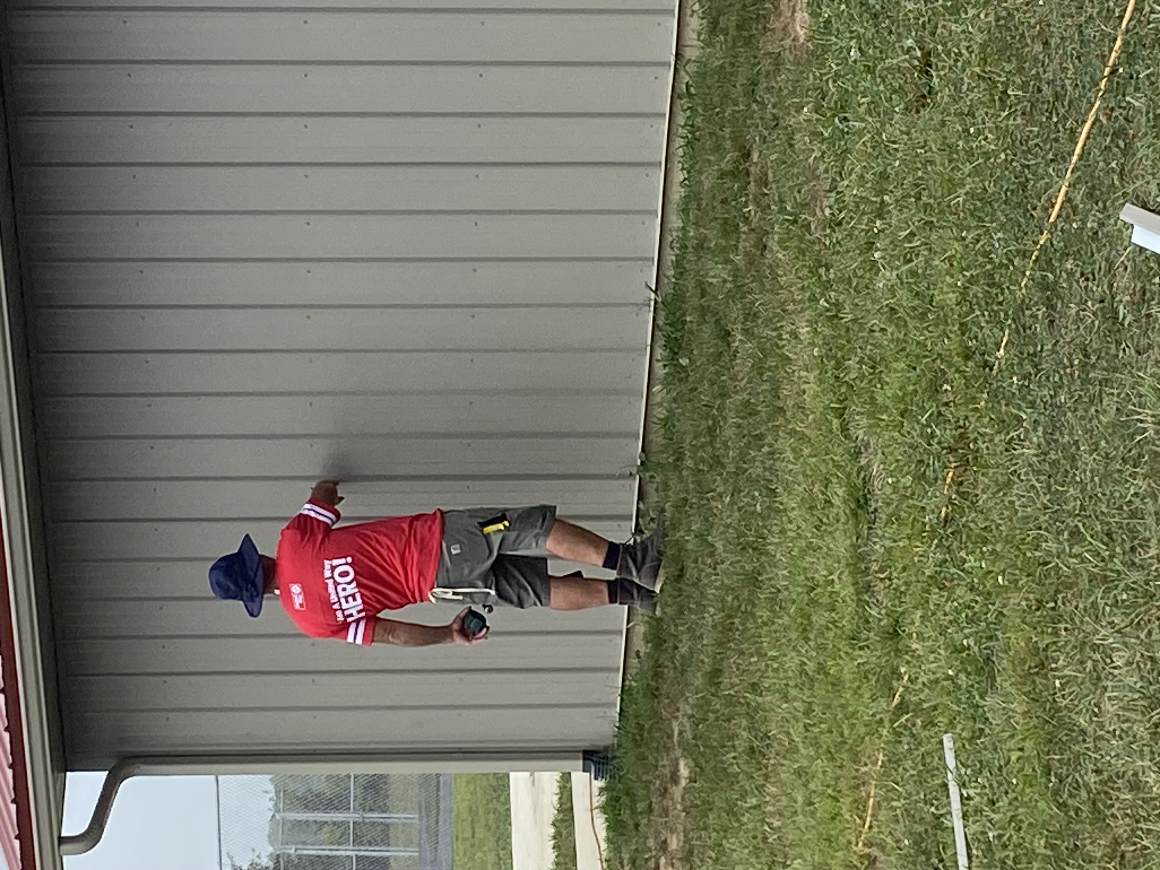 man in hat working on siding a building