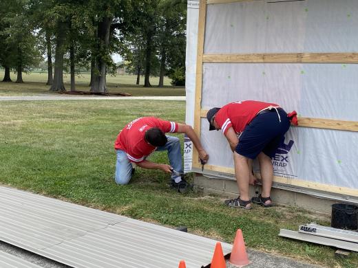 two men working on the side of a building