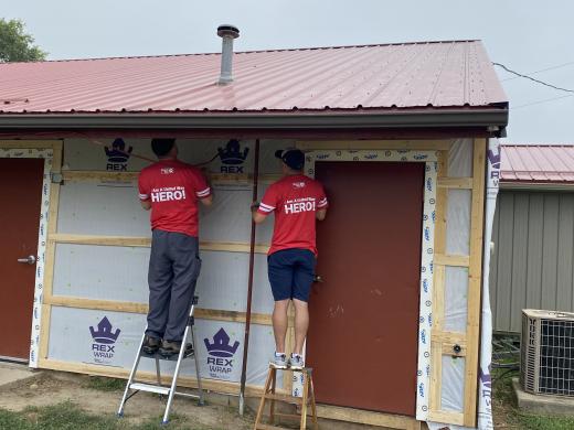 two men working on siding a building